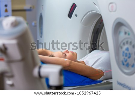 Pretty, young woman goiing through a Computerized Axial Tomography (CAT) Scan medical test/examination in a modern hospital (color toned image; shallow DOF) Royalty-Free Stock Photo #1052967425
