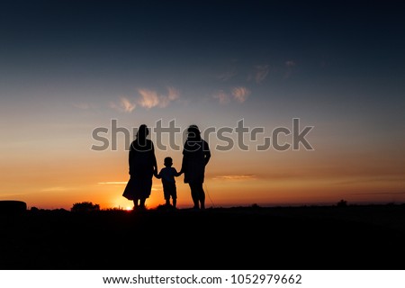 Mother, son and grandmother walking together, then stopping and watching the great view of the sunset. They holding their hands.