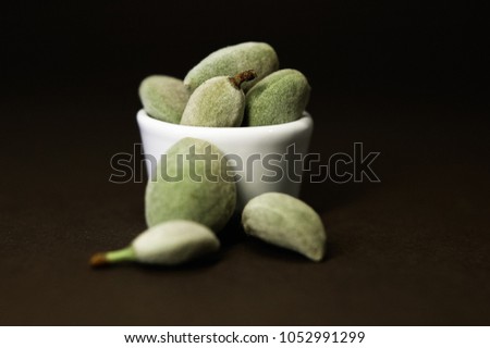 Raw, unpeeled, green almond fruits or drupes with green-grey, downy coat, called hull