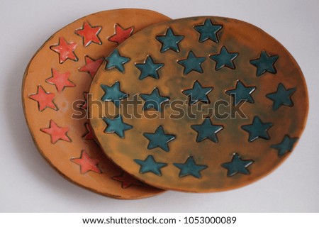 Close-up of ceramic handmade plates with a blue and red star print on a white background. Ceramic design. Star Print. 