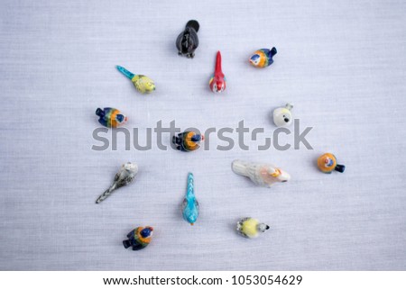 Some kinds of colorful ceramic birds standing on the white floor.