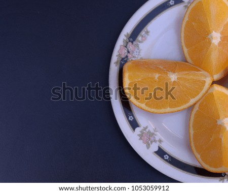Oranges in a round plate on a navy blue background