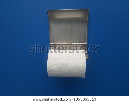 The silver toilet paper holder has white roll paper on a blue background