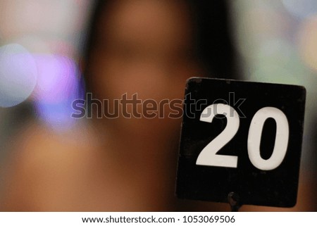Black tag number and blurred background of woman and light bokeh abstract background