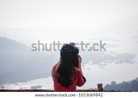 
Soft focus and  over light of Nature on morning travel woman in red look and camera take picture landscape at Mekong River from the top with Fog over mountain,Nongkhai Thailand,HDR Film  style.