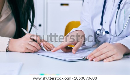 Patient signing medical contract. Female doctor explains how to fill medical form.