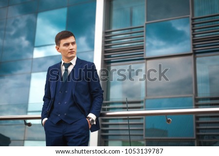 Thoughtfull asian groom in a dark blue suit waiting for his bride against the backdrop of the architecture of the city. concept of a strong successful man Royalty-Free Stock Photo #1053139787