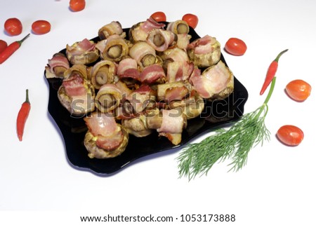 Mushrooms stuffed with bacon and cheese, on a black dish, ready to eat, isolated on white background.
