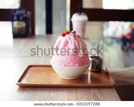 Pink milk kakigori or Japanese shaved ice dessert flavored, Topped with pink whipped cream, blueberry and red currant, same as Bingsu Korean dessert.