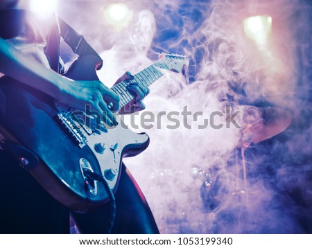 Performance of the rock band. The guitarist plays solo. The bass player plays solo. Drummer. Bass drum. Close-up. Royalty-Free Stock Photo #1053199340