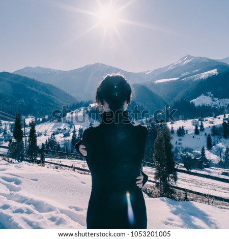 Lonely girl in the mountains in winter. Portrait from behind. Beautiful light. Atmospheric photography