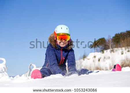Photo of female athlete in helmet sitting at snowdrift
