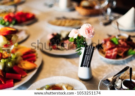 wedding table with delicious dishes and a small vase with roses