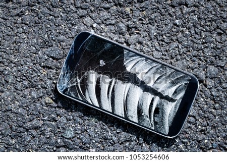 Road with broken phone smartphone cracked screen fell on asphalt ground