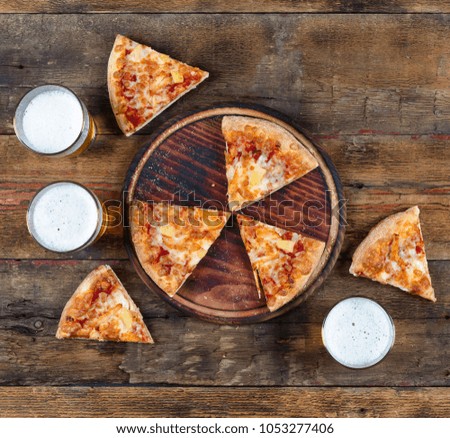 Appetizing pepperoni pizza and light beer on a wooden table. Concept: eating out, pizzeria, oktoberfest