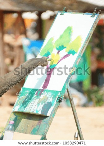 Young elephant drawing a picture of a tree with color paint 
