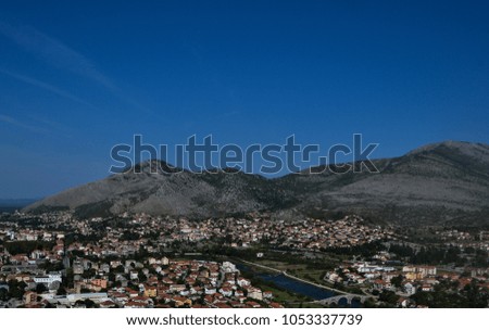 
View of the city from the observation deck.A city in Bosnia surrounded by mountains.The Old Bridge in Mostar with emerald river Neretva.Bosnia and Herzegovina.Beautiful mountain landscape.