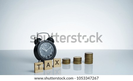 TAX Conceptual image with Black retro alarm clock with coins and wooden text block