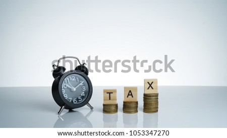 TAX Conceptual image with Black retro alarm clock with coins and wooden text block