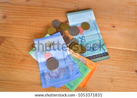Mixed value of Malaysian Ringgit Bank Notes and coins on wooden background.