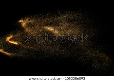 Abstract sand cloud. Golden colored sand splash agianst dark background. Yellow sand fly wave in the air. Sand explode on black background ,throwing freeze stop motion.