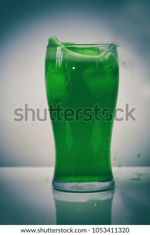 Glass of green beer against a light grey background