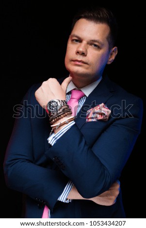 Portrait of confident handsome businessman with crossed arms with hand near his chin on black background