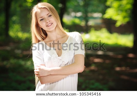 Beautiful smiling girl standing with folded hands over green summer background