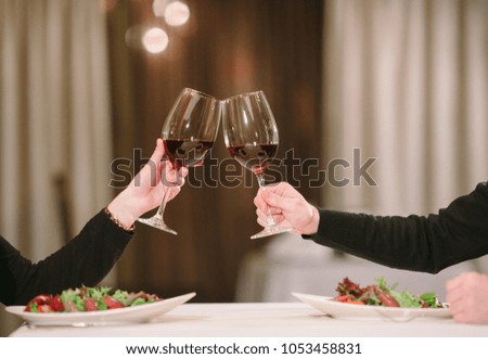 Man and woman drinking red wine. In the picture, close-up hands with glasses. 