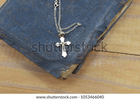 Christian cross with the old holy Bible on the table
