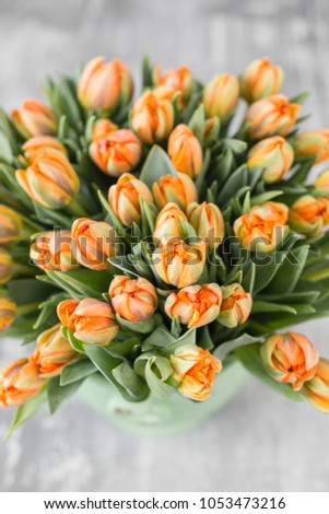 Tulips of orange color in green vase. Big buds of multicoloured tulips. Floral natural backdrop. Bicolour tulips filled picture. Unusual flowers, unlike the others. Shallow focus.