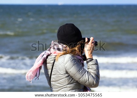 Girl with a camera on the background of the sea. Without a face
