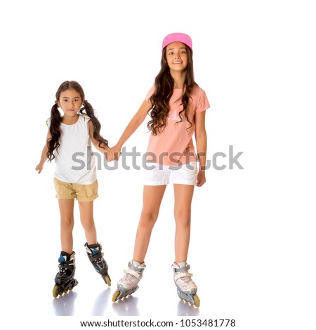 Two beautiful little Asian girls skate on roller skates. The concept of advertising sports goods, a healthy lifestyle, a happy childhood. Isolated on white background.