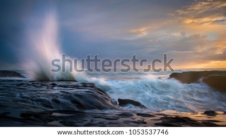 Splash waves at Sunset, at wild west coast of Auckland New Zealand Royalty-Free Stock Photo #1053537746