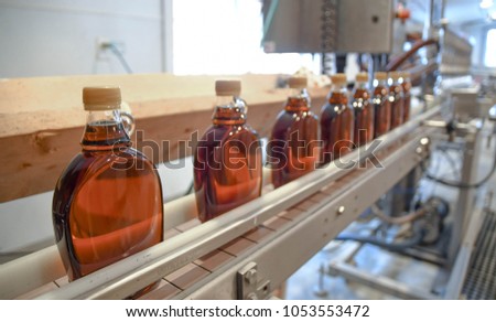 Bottles of maple syrup line a rack in a small syrup production facility on a farm in New Hampshire, USA.  Royalty-Free Stock Photo #1053553472