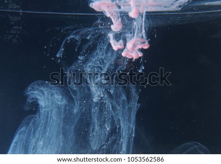 A drop of pink paint dissolves in water. The abstract photograph. Close up.