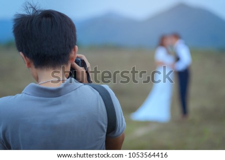 wedding photographer in action, wedding photographer takes pictures of the bride and groom in nature. Behind the scene of photography working concept.