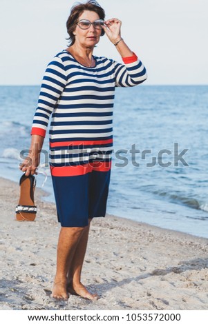 Pretty elderly woman in sunglasses on vacation by sea 