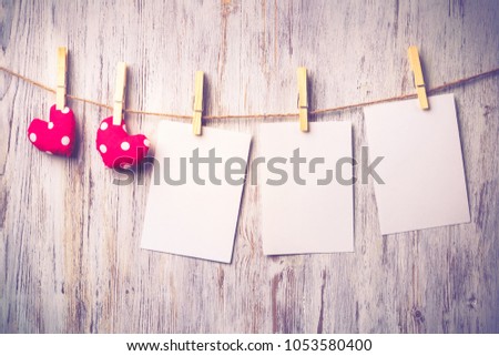 Blank sheet of paper hand made heart pinned to rope on wooden background