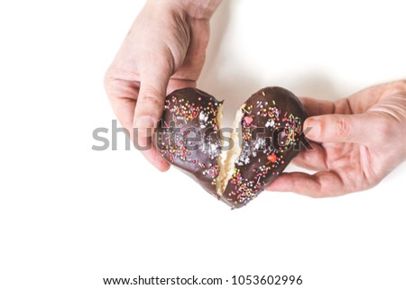 Heart in half. Hands share a chocolate gingerbread in the form of a heart in two pieces on a white background
