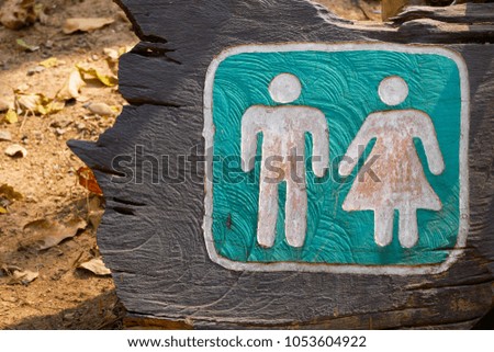 A toilet room sign on a wood log