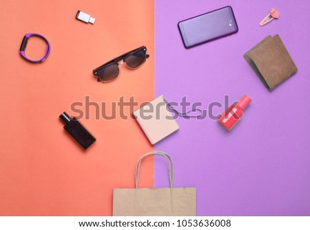 Paper bags and many purchases of gadgets and accessories on a colored background: sunglasses, smartphone, smart bracelet, powel bank, usb flash drive, wallet. Consumer concept. Top view.