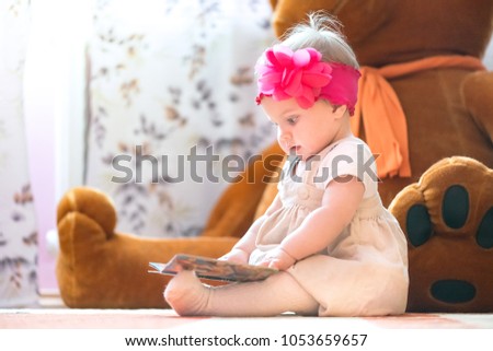 10 months old baby girl examining a book Royalty-Free Stock Photo #1053659657