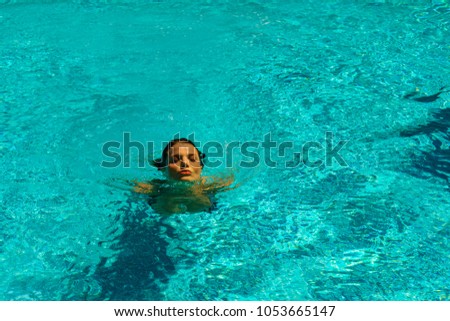 Beautiful tanned woman in swimwear relaxing in swimming pool spa.