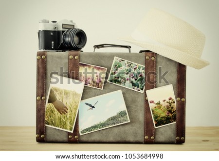 Image of old vintage luggage, fedora hat and vintage old photo camera with nature photos over wooden floor