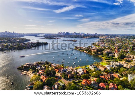 Sydney inner west suburb Drummoyne and beyond on shores of Parramatta river flowing into Sydney harbour with distant city CBD on horizon in elevated aerial view. Royalty-Free Stock Photo #1053692606