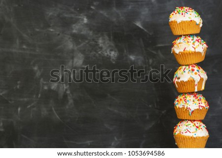 Easter cakes decorated with white icing and colorful sugar on a dark background. Easter background. Frame