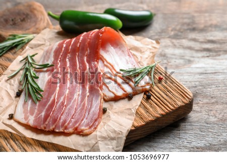 Board with raw bacon on table, closeup Royalty-Free Stock Photo #1053696977