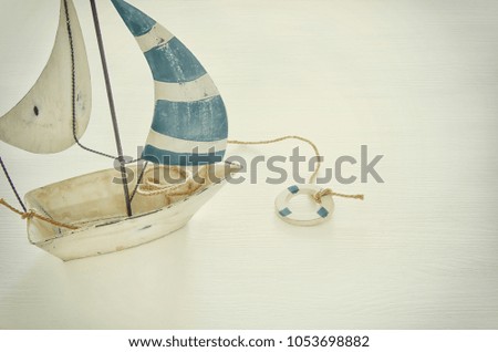 nautical concept with white decorative sail boat over white wooden table. Vintage filtered image