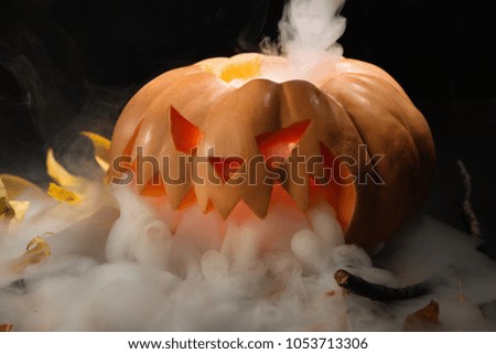 Halloween pumpkin lantern with dry leaves with burning candles on black background